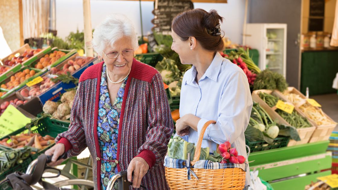 Uniting care worker supporting senior woman with food market shopping