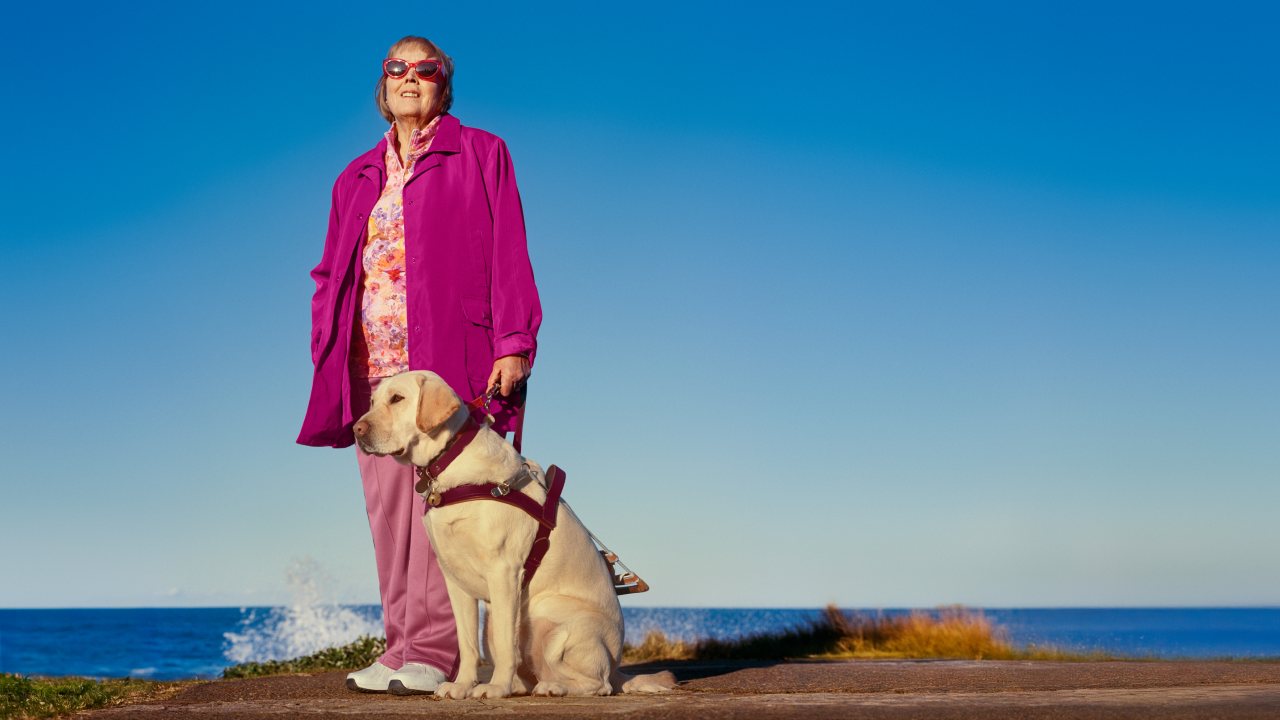 Senior woman at the beach with her guide dog Senior woman at the beach with her guide dog