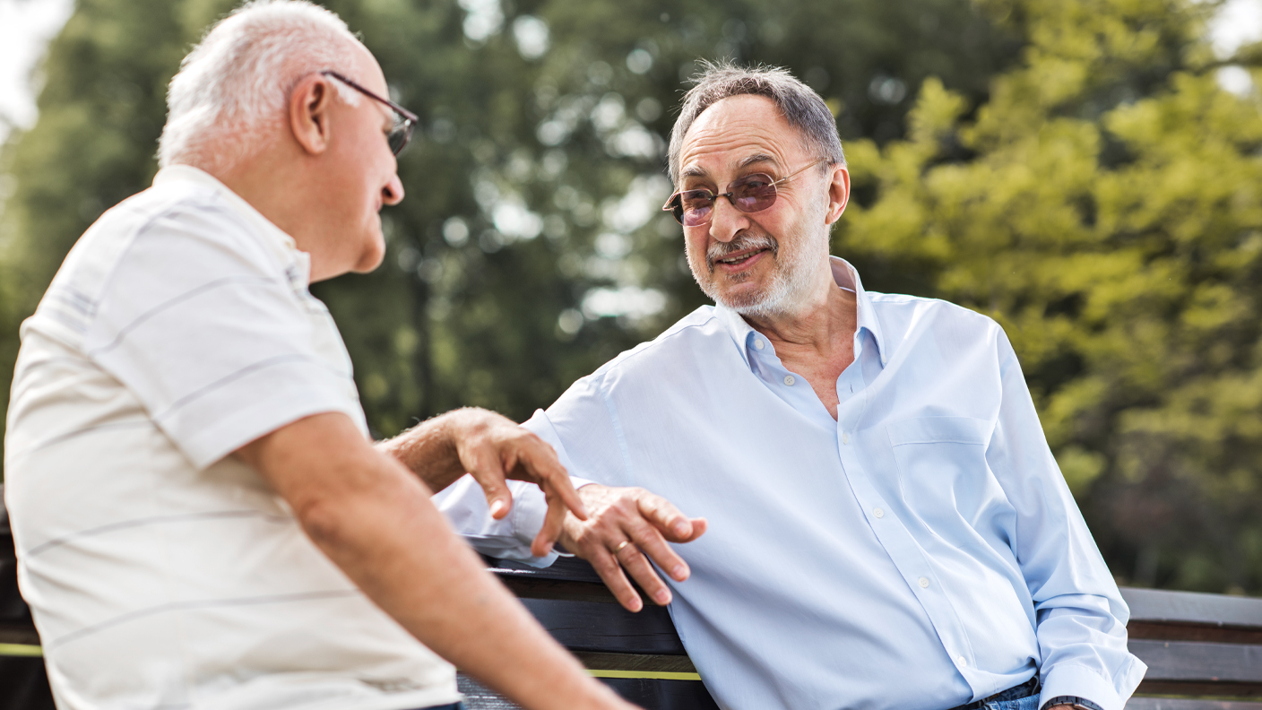 Two senior men enjoying a chat on a park bench Two senior men enjoying a chat on a park bench
