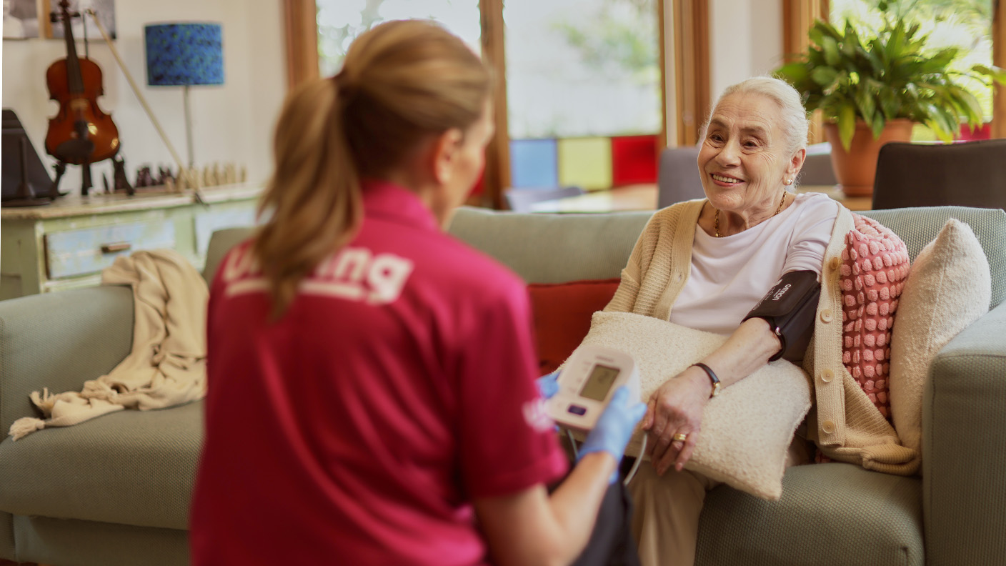  Uniting nurse checking senior woman's blood pressure at home