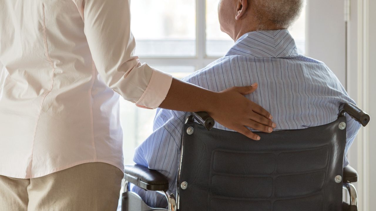 Uniting care worker comforting senior man in wheelchair
