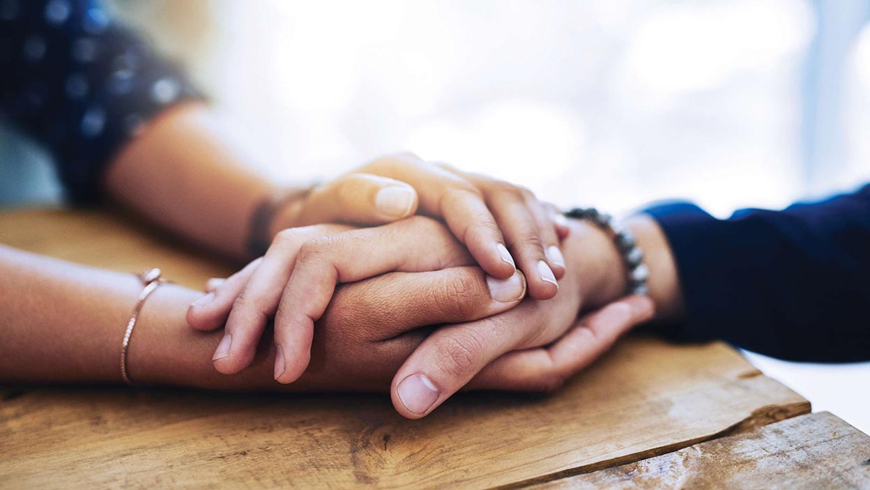 Two people holding hands across a table