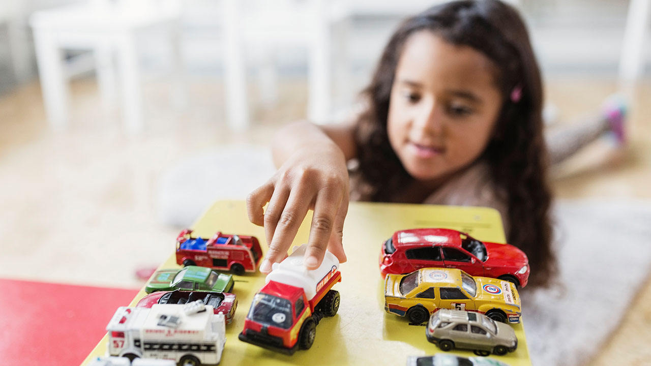 A young girl playing with her toy cars