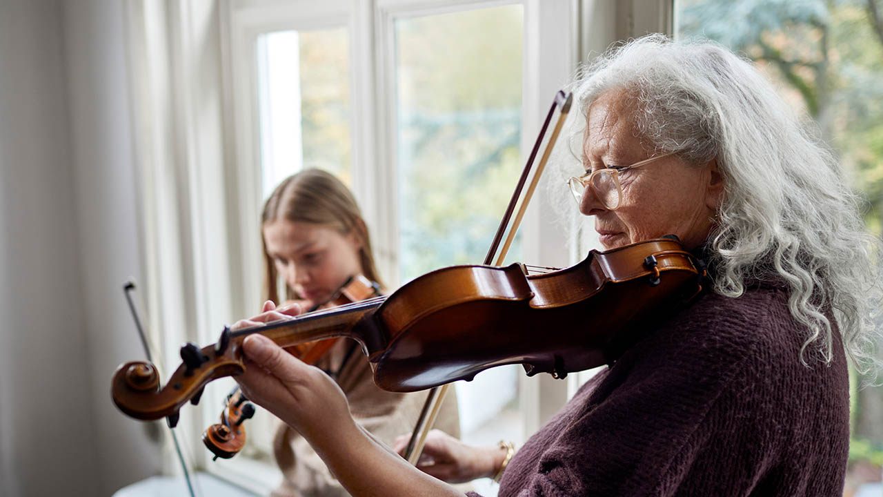 Senior woman and young girl playing violins together