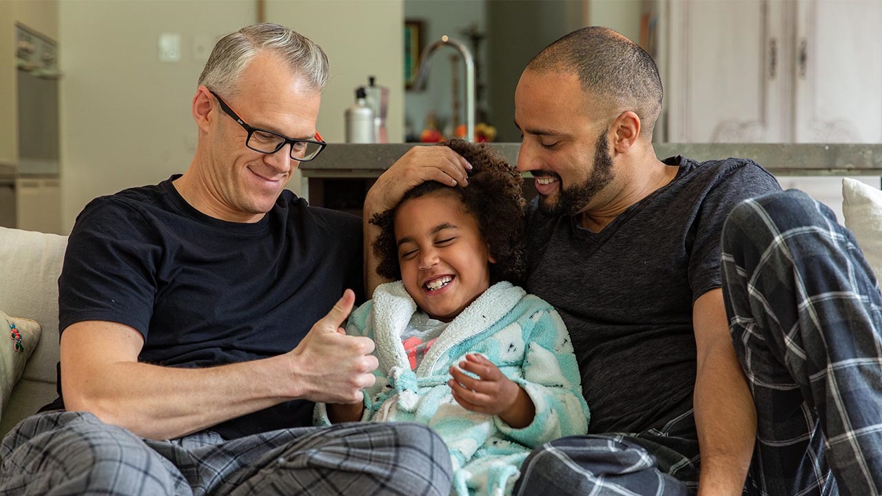 Two male adults caring for a child Two male adults caring for a child