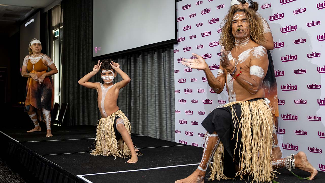 Mixed age Aboriginal dance group performing.