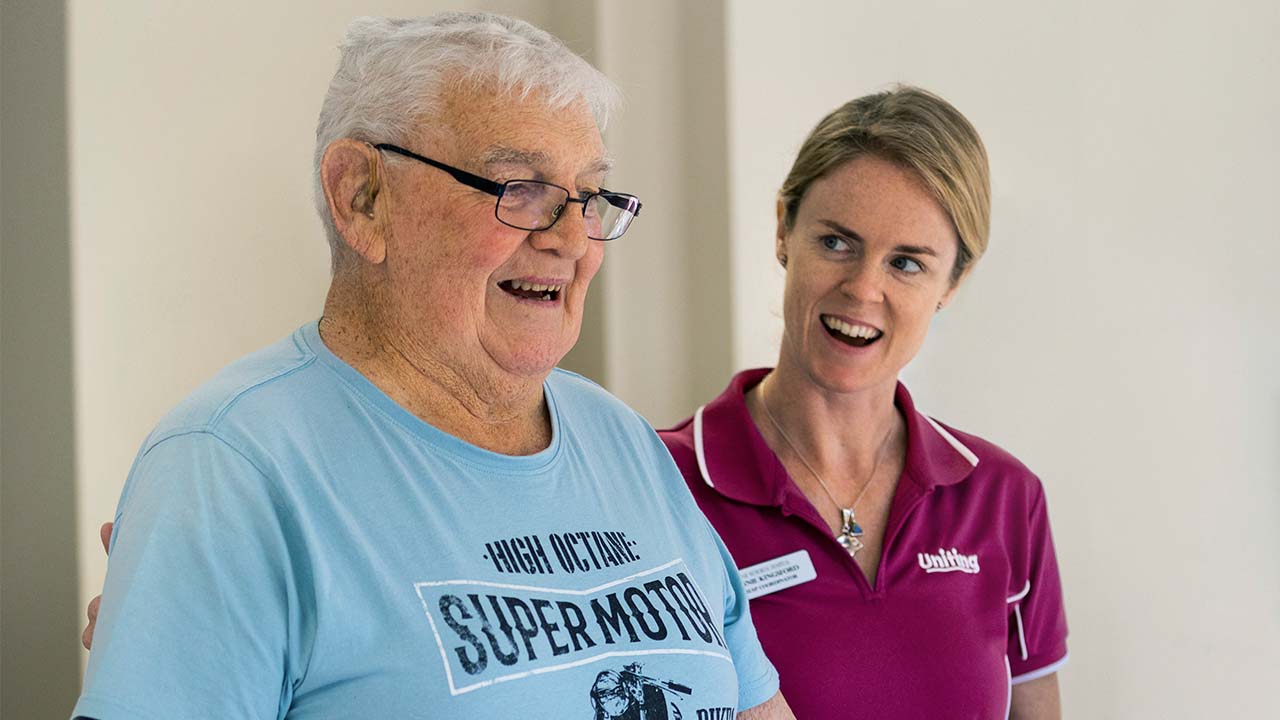 Elderly man and an aged care worker share a joke