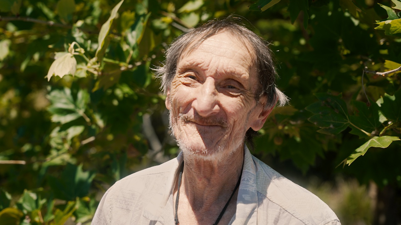 A homeless man looks at the camera and smiles.