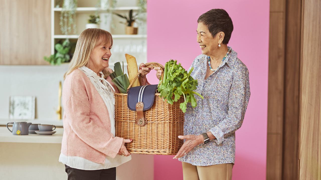 Two women holding a basket with vegetables