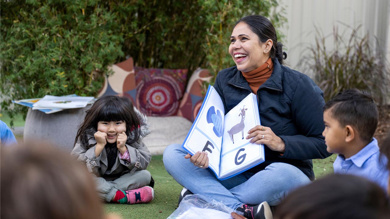 Early childhood educator reading a book to group of children