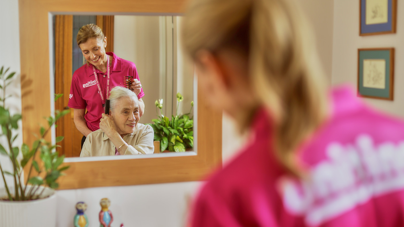 A care worker brushes an elderly woman's hair. A care worker brushes an elderly woman's hair.