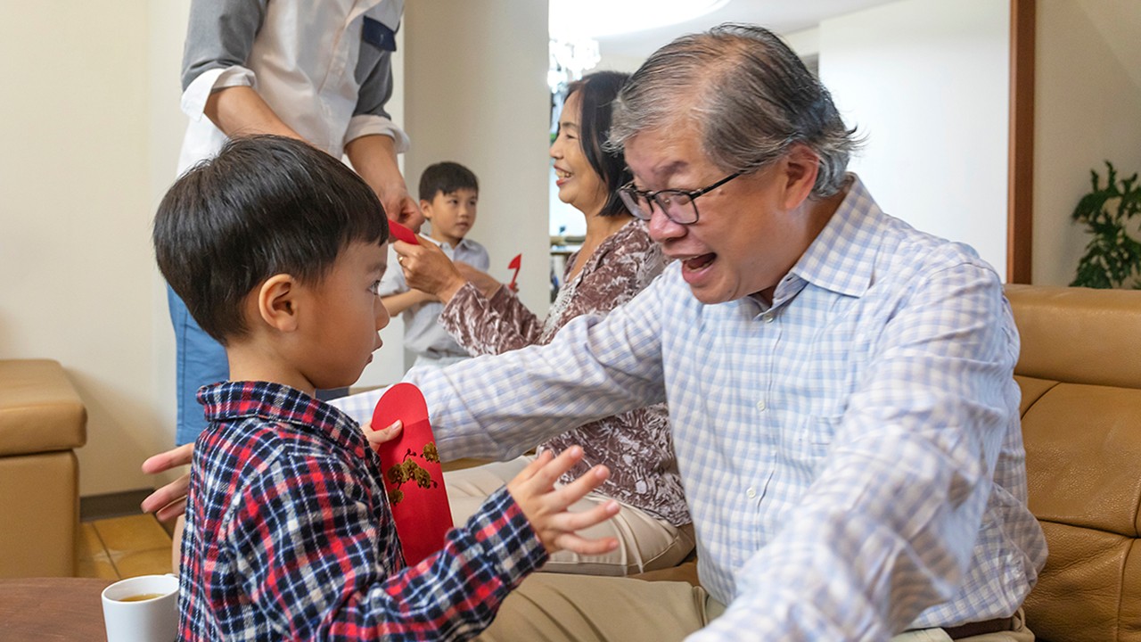 Happy Grandson Hugging His Grandfather When Giving Lucky Red Envelopes for CHinese New Year